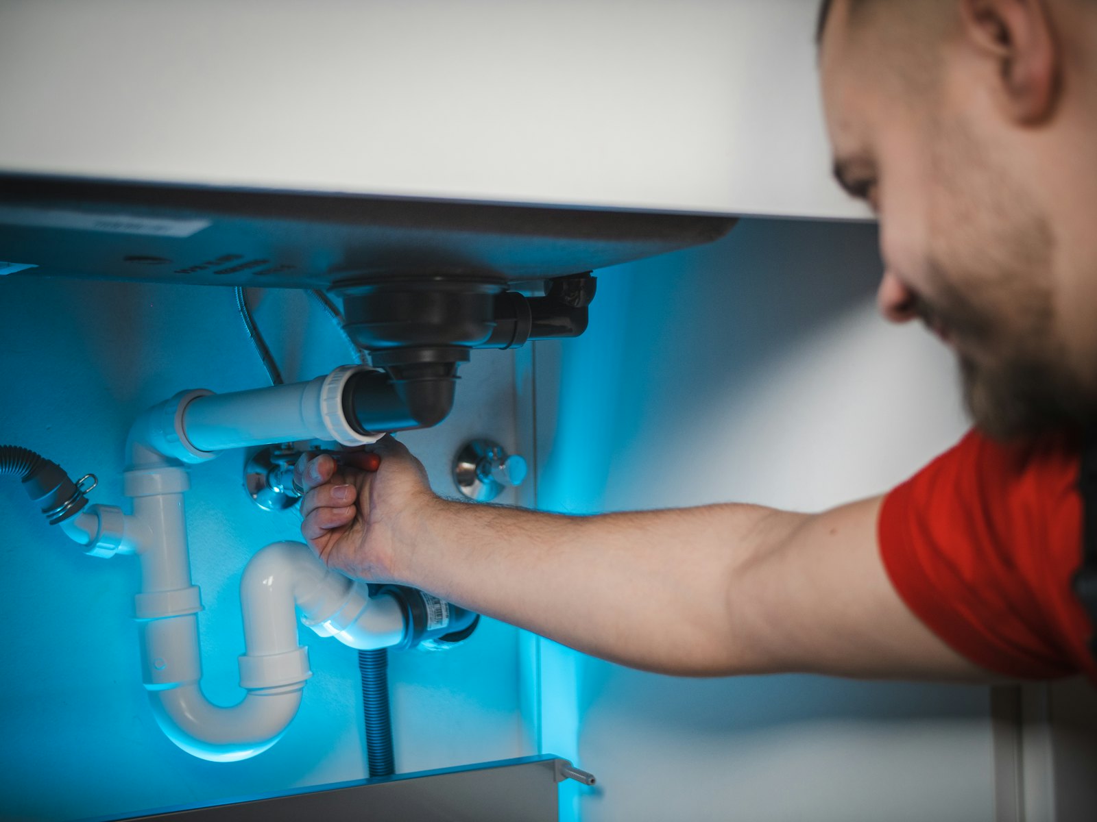 A plumber fixing pipework under a sink