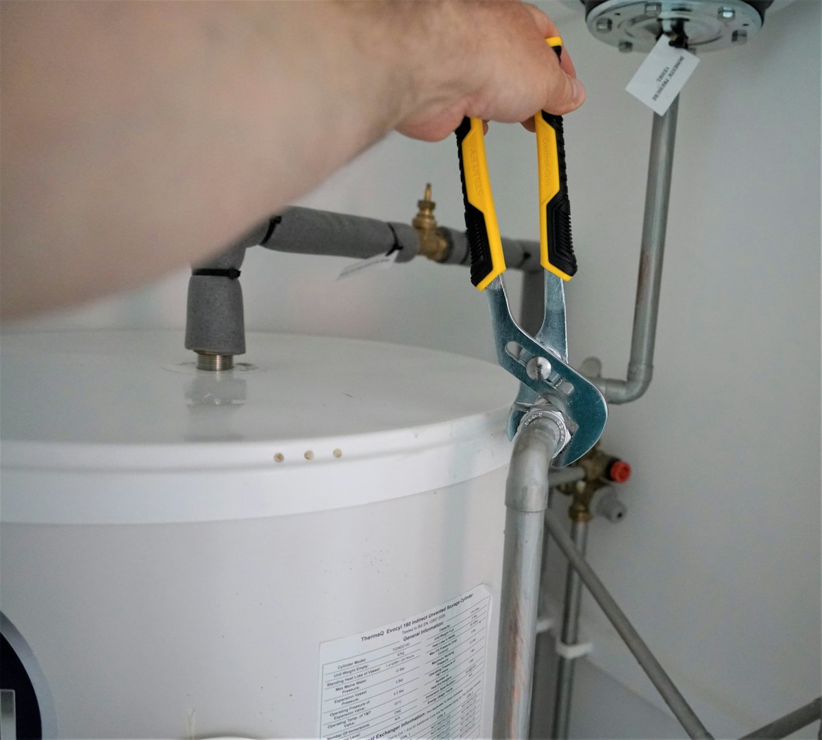 A wrench tightening a pipe fitting on a hot water cylinder